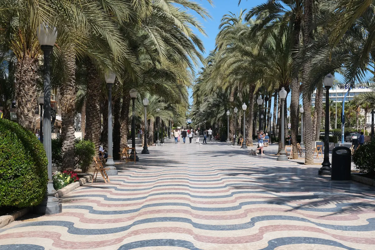 Mramorová dlažba s vlnovitým vzorem na Explanada de España v Alicante v červené, šedé a krémové barvě mezi řadami vysokých palem